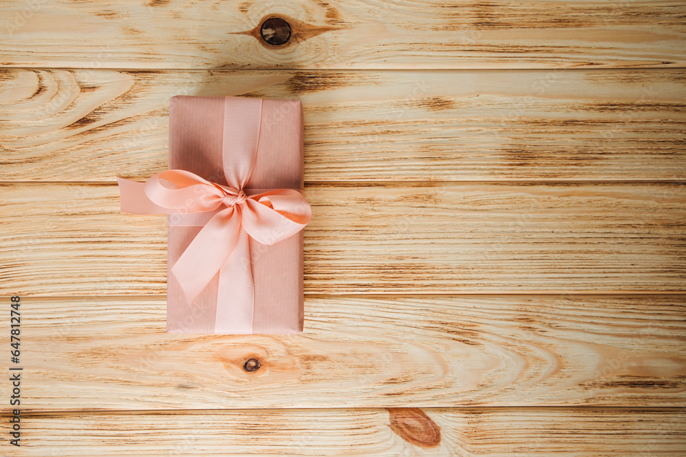 Background for greetings. Gift wrapping in soft pink paper on a light wooden background with copy space. Top view Background for greetings. Gift wrapping in soft pink paper on a light wooden background with copy space. Top view
