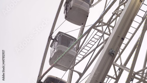 modern ferris wheel with closed cabins at carnival with blue sky no clouds in the background illuminated wide angle close up shot