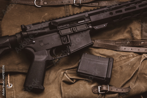 Modern automatic carbine and backpack on a wooden table. A set of fighter ready for any battle conditions.