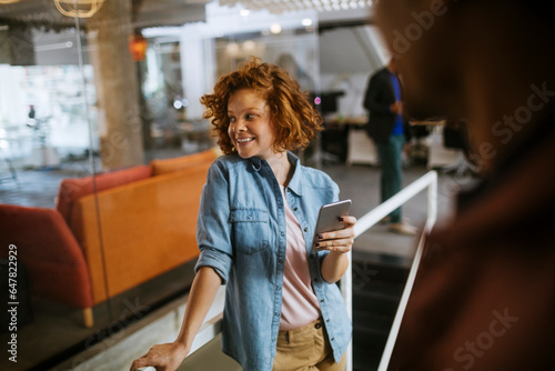Young Caucasian woman using a smartphone in the office of a startup company