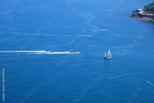 Jet skis and sailboat crossing the blue Cantabrian Sea
