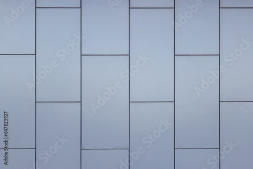 Outside wall of building covered with grayish blue painted metal rectangular panels - full-frame background and flat texture.