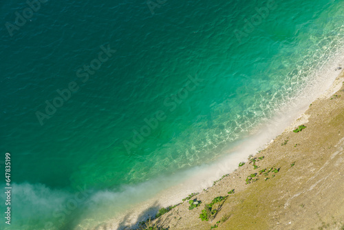 Aerial view of the steep coast with white sand on the shore of a clean and beautiful turquoise sea. Tropical sea beach in Indonesia. An empty deserted beach for a family holiday. Copy space