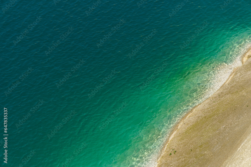 Obraz premium Aerial view of the steep coast with white sand on the shore of a clean and beautiful turquoise sea. Tropical sea beach in Indonesia. An empty deserted beach for a family holiday. Copy space