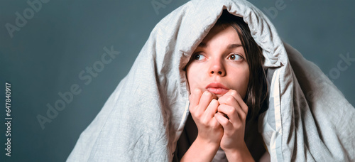 Young girl hugs a pillow and hid under a blanket from all problems, procrastinating, millennials generation. Woman covered with a blanket and is worried about insomnia, poor sleep, getting stress. photo