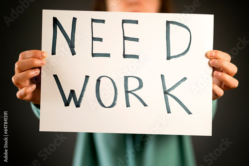 A girl holds a paper with a text "need work" in her hands.