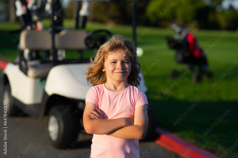 Kid in golf park near golf cart. Child summer vacation. Lifestyle closeup portrait of funny kids face outdoors. Summer kid outdoor portrait. Close up face of cute child.