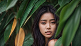 Portrait of a beautiful Asian girl against a background of tropical leaves