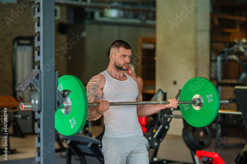 Handsome fit muscular caucasian man workout in the gym with weight pumping up muscles. Fitness and bodybuilding sport. Bodybuilder with dumbbells at gym, hard workout.