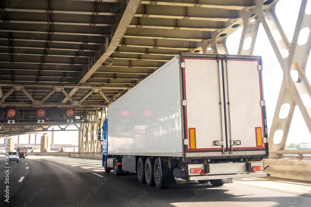 Cargo truck is driving along road. Automobile cargo transportation. Transportation of goods by truck. Truck is driving along overpass. Multi-tiered road. Logistics vehicles. Lorry for importing goods Cargo truck is driving along road. Automobile cargo transportation. Transportation of goods by truck. Truck is driving along overpass. Multi-tiered road. Logistics vehicles. Lorry for importing goods