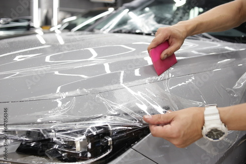 A car wrapping specialist applies a polyurethane film to the car. Selective focus. PPF protective film against chips and scratches. Car wrapping. 