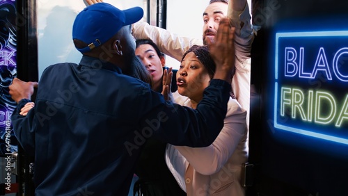Fotografie Diverse shoppers argue with security guard, waiting for black friday deals outside of department store