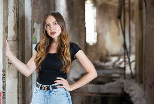 Young brown haired woman posing in derelict building. Long haired caucasian woman in deserted house.