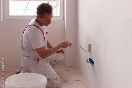 Bilde på lerret Construction worker painter man with paint roller in his hand and buckets of pro