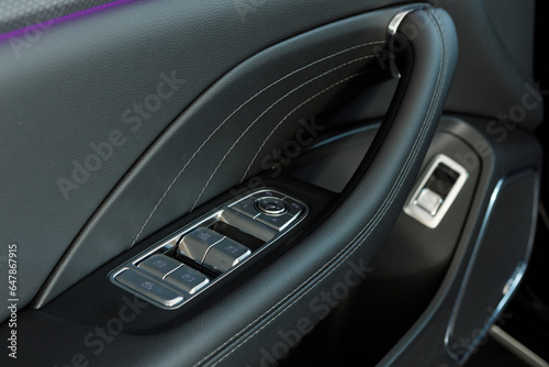 Close up photo of the premium-segment car door inner panel with Hi-Fi speaker. Metal buttons of the window risers panel on the door armrest