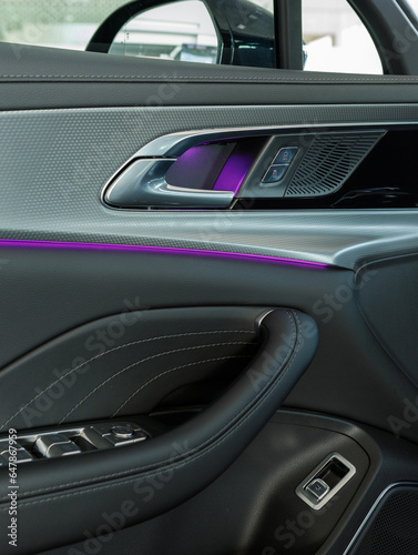 vertical photo of a door panel with ambient purple lighting and aluminum trim in a premium car © AvokadoStudio