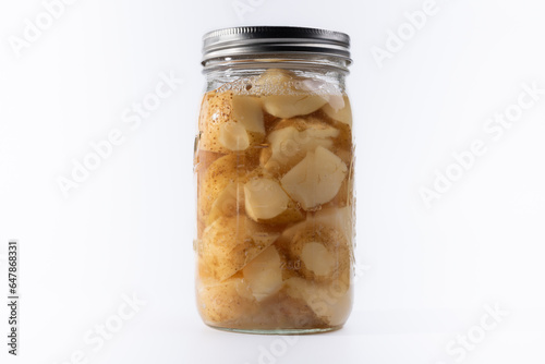 Single jar of freshly canned potatoes on white background.