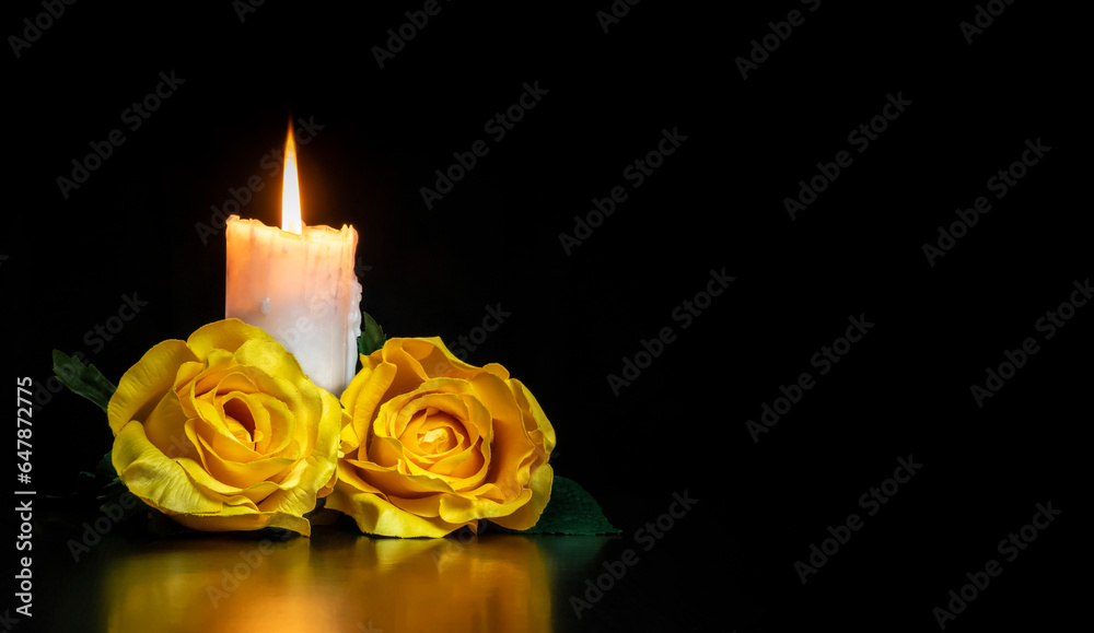 LIGHTED CANDLE AND YELLOW ROSES ON DARK BACKGROUND. CONDOLENCE CARD FOR ALL SOULS DAY. COPY SPACE. LIGHTED CANDLE AND YELLOW ROSES ON DARK BACKGROUND. CONDOLENCE CARD FOR ALL SOULS DAY. COPY SPACE.