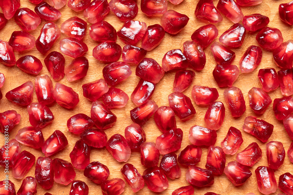 Pomegranate seeds background. Close-up of pomegranate seeds in wooden plate. Pomegranate seeds background. Close-up of pomegranate seeds in wooden plate.