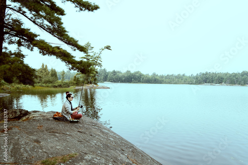woman fishing on the rocks in the heart of nature, freedom concept