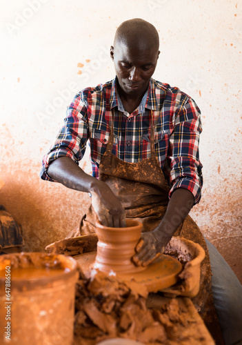 Professional male potter making bowl on potters wheel in pottery studio