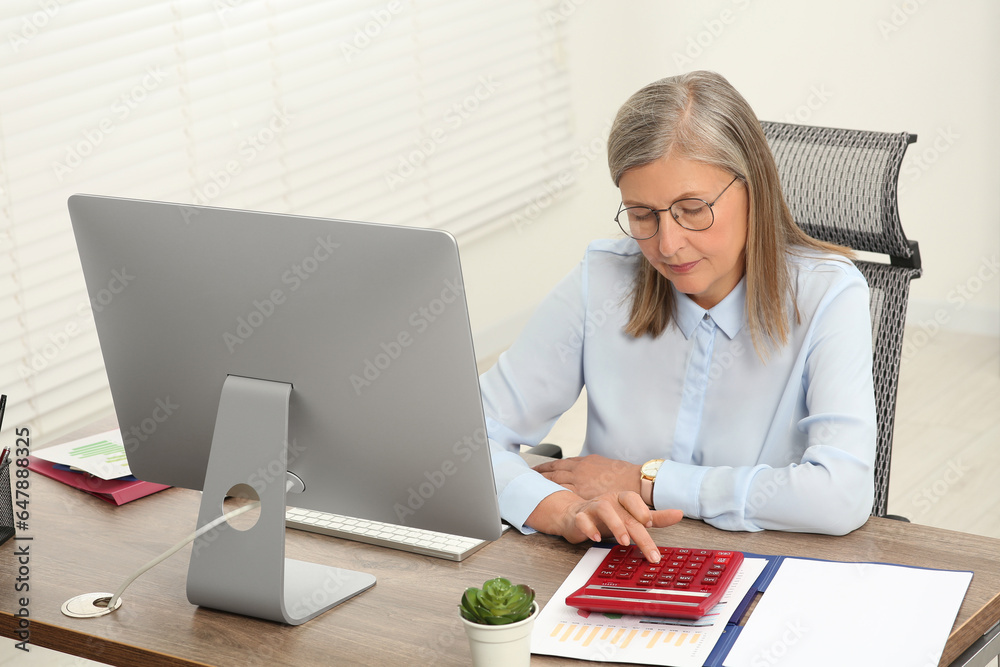 Senior accountant working at wooden desk in office Senior accountant working at wooden desk in office