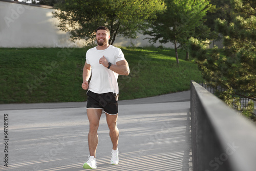 Smiling man running outdoors on sunny day