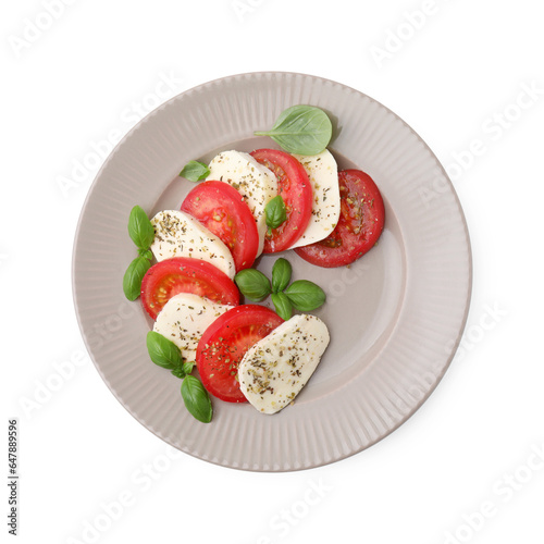 Plate of delicious Caprese salad with tomatoes, mozzarella, basil and spices isolated on white, top view
