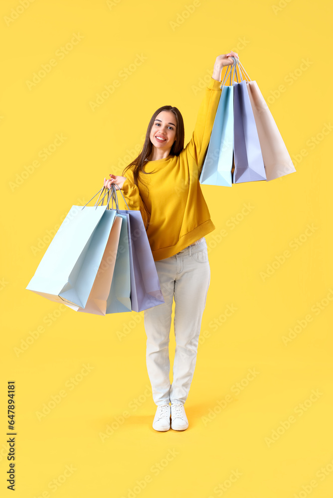 Happy young woman with shopping bags on yellow background Happy young woman with shopping bags on yellow background