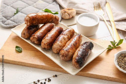 Plate of tasty grilled sausages on white wooden background