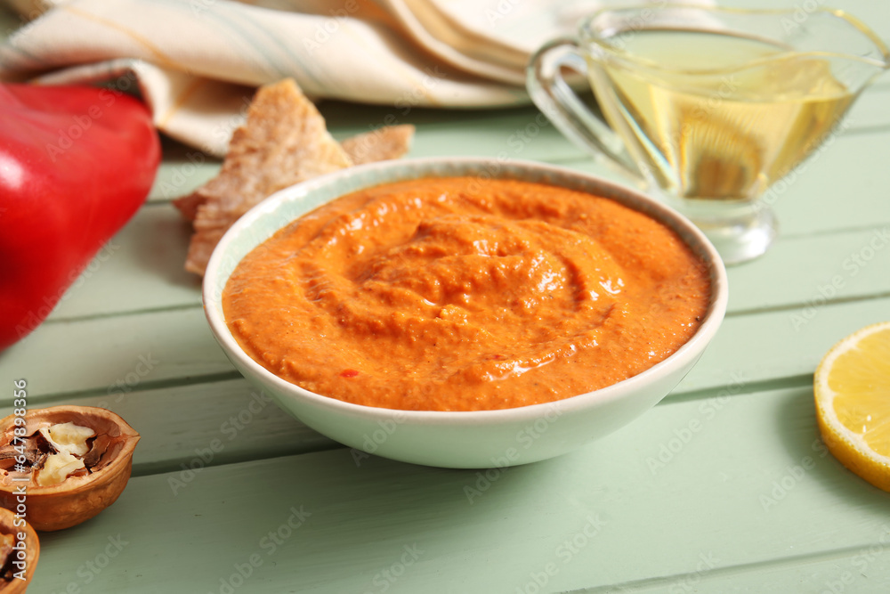 Bowl of tasty muhammara on green wooden background Bowl of tasty muhammara on green wooden background