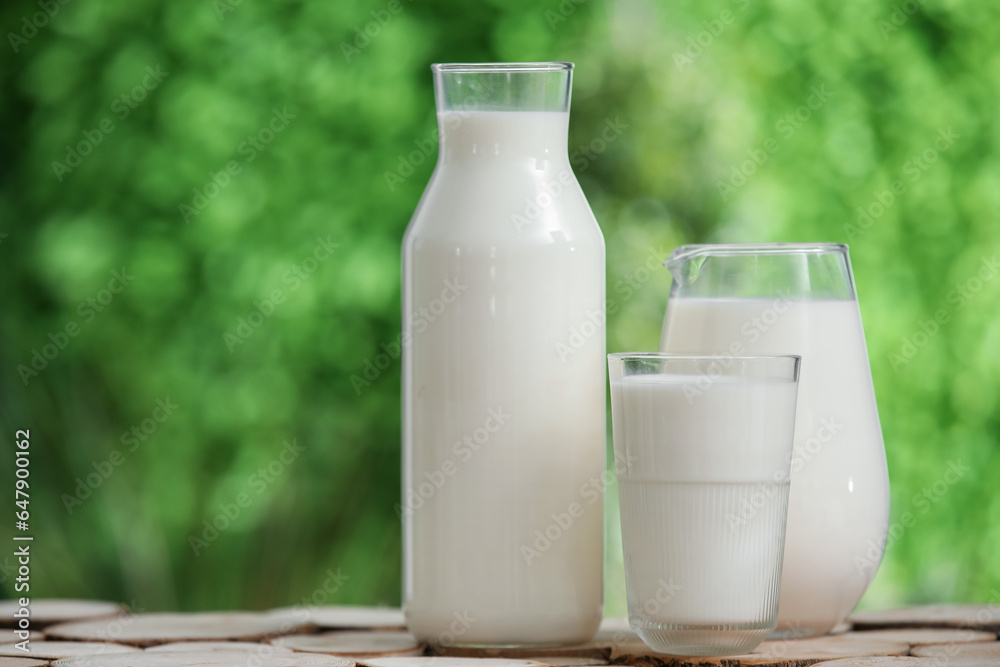 Glass and bottle of fresh milk on wooden table outdoors Glass and bottle of fresh milk on wooden table outdoors