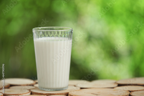 Glass of fresh milk on wooden table outdoors
