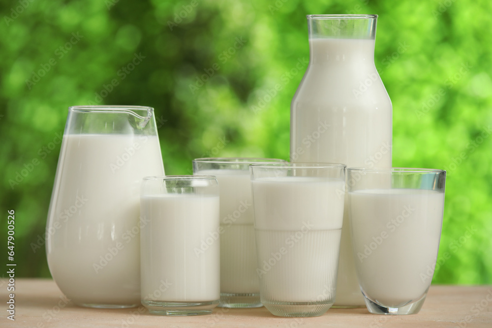 Glasses and jug of fresh milk on beige table outdoors Glasses and jug of fresh milk on beige table outdoors