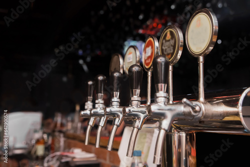 A line of taps of draft beer in the bar of the establishment, close-up