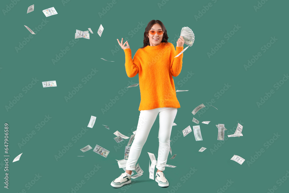 Young Asian woman with dollar banknotes on green background