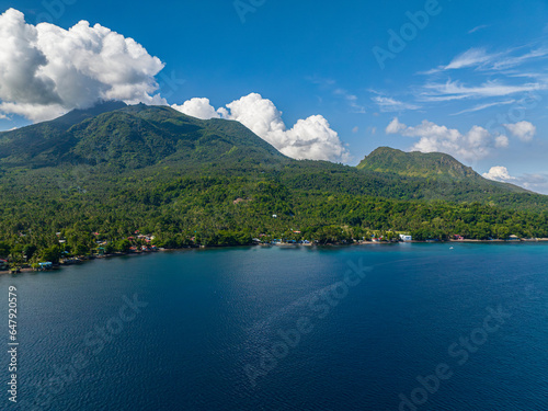Tropical island with houses on coastline and blue sea of Camiguin Island. Philippines.