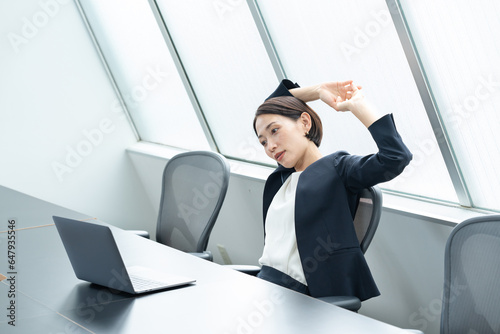 オフィスで伸びをする女性 photo