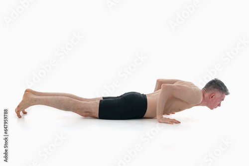Side view of man wearing sportswear doing Yoga exercise against white background. Chatvari, Ashtanga yoga