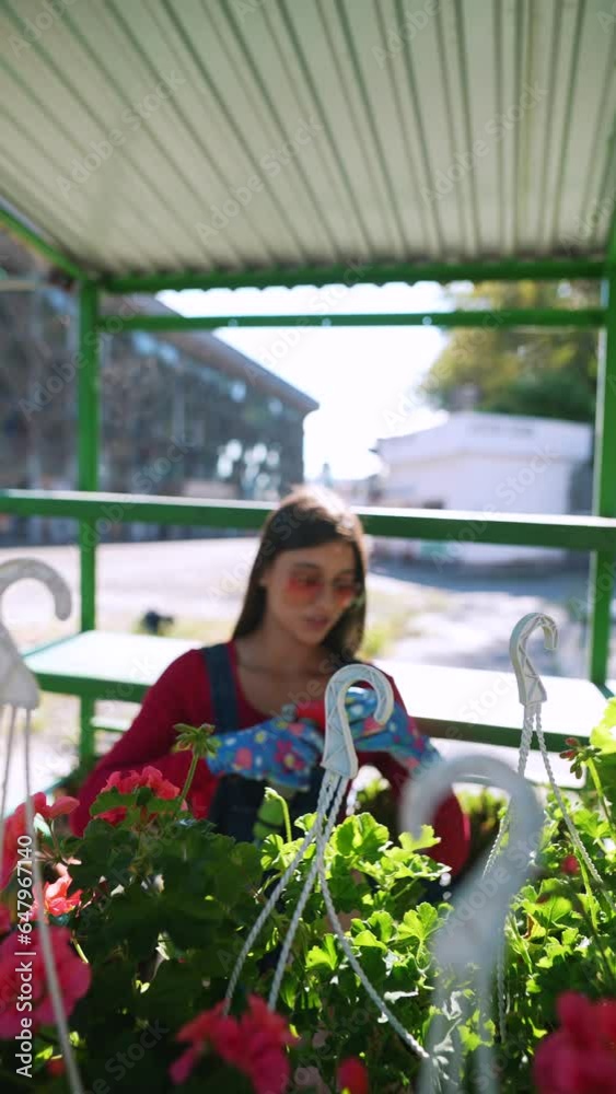In the lively market setting, a lady is carefully misting water onto the vases.