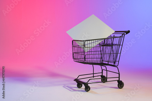Shopping trolley with blank canvas and copy space over neon purple background