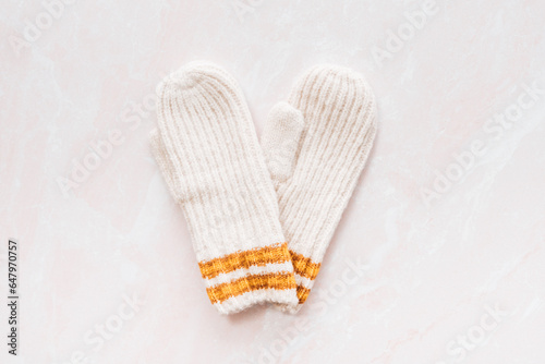 A flatlay of two cream and mustard mittens in the shape of a hea