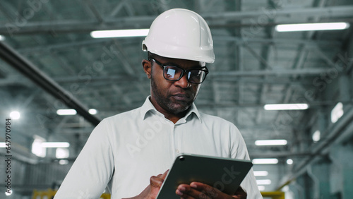 Photos Serious thoughtful African-American hard-working male employee manufacturer factory manager engineer using tablet