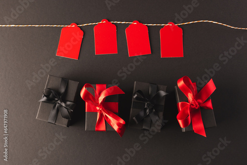 Red gift tags on pegs and black gift boxes with copy space over black background