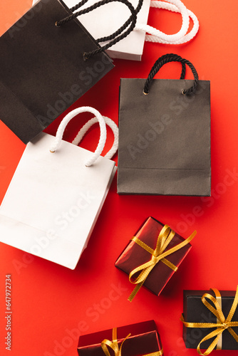 Vertical image of gift boxes with ribbon, gift bags with copy space over red background
