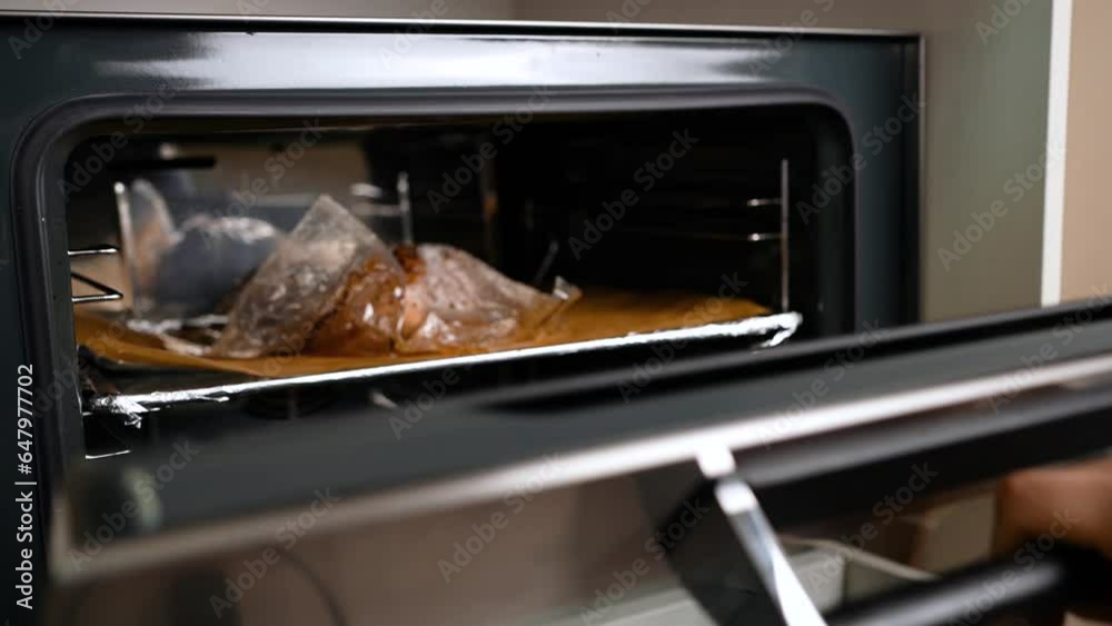 Slow motion, opening the oven and taking out the baking tray with baked chicken. Slow motion, opening the oven and taking out the baking tray with baked chicken.
