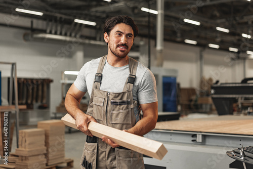 Young carpenter man looking and choosing wood plank at workshop in carpenter wood factory