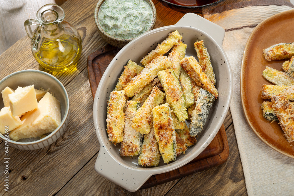 Healthy zucchini fries with yogurt and herbs sauce on a wooden table