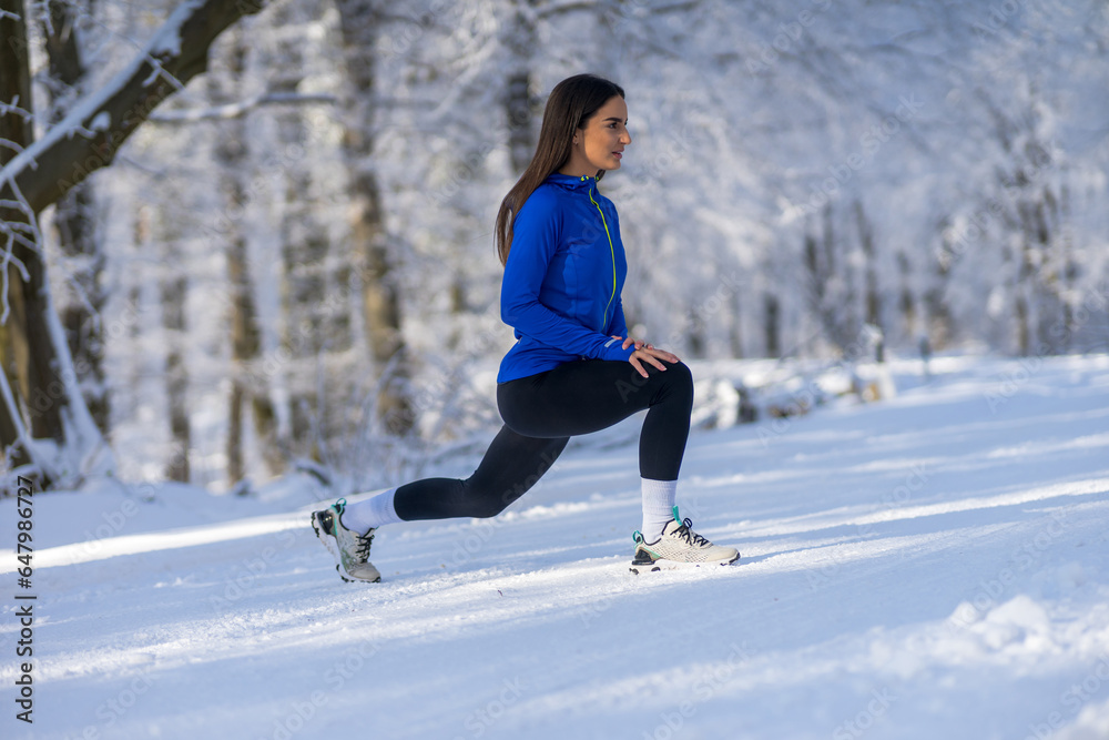 Young sportswoman in perfect shape stretching leg in nature at snowy winter day. Young sportswoman in perfect shape stretching leg in nature at snowy winter day.