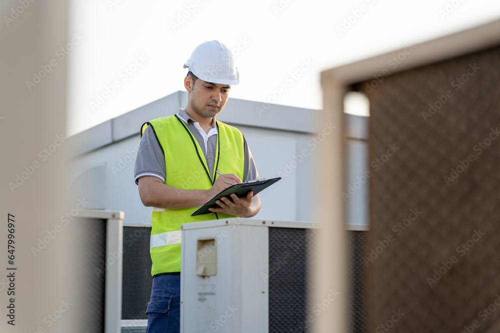 Asian maintenance engineer works on the roof of factory. contractor inspect compressor system and plans installation of air condition systems in construction. Checklist, inspector, control Asian maintenance engineer works on the roof of factory. contractor inspect compressor system and plans installation of air condition systems in construction. Checklist, inspector, control